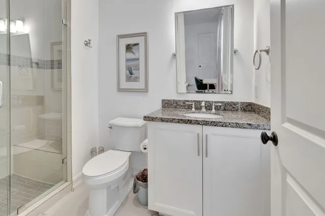 a bathroom with a granite countertop sink mirror vanity and toilet