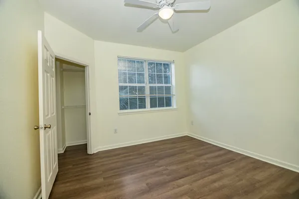 an empty room with wooden floor closet and windows