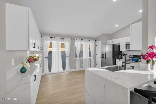 a kitchen with a sink dishwasher and a refrigerator with wooden floor
