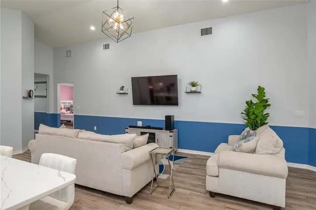 a living room with furniture a chandelier and a flat screen tv