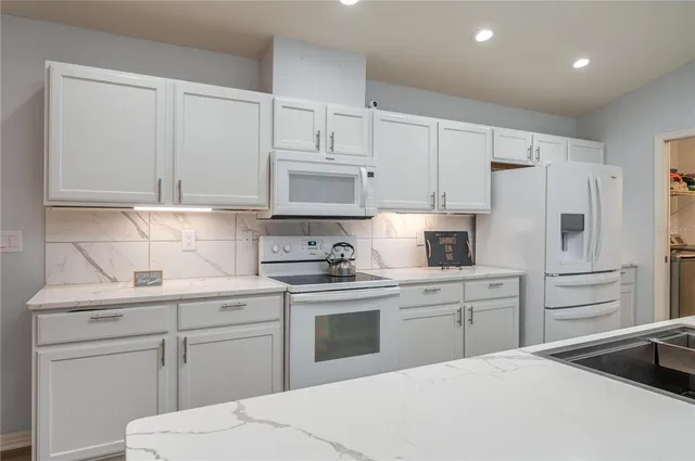 a kitchen with white cabinets and white appliances