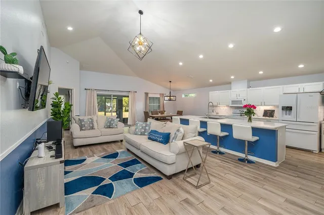 a living room with furniture kitchen view and a wooden floor