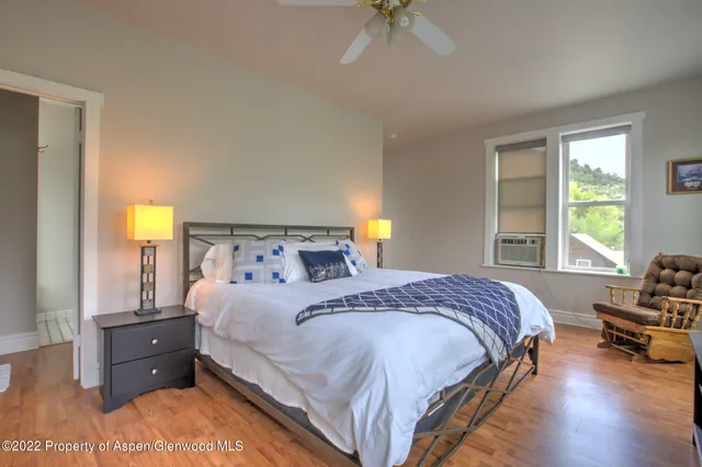 a bedroom with a bed a chandelier and a dresser with wooden floor