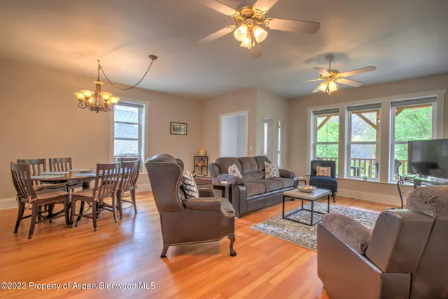a living room with furniture a chandelier a dining table and a large window