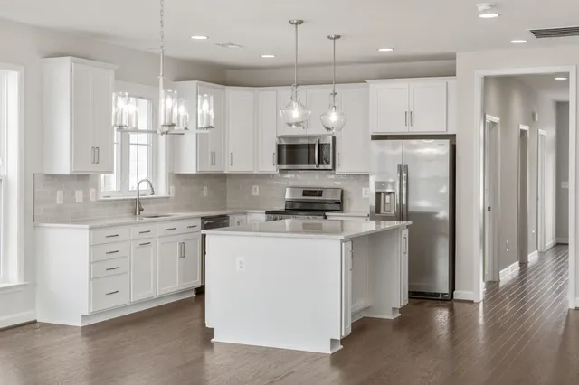 a white kitchen with a sink a stove oven a refrigerator with white cabinets and wooden floor