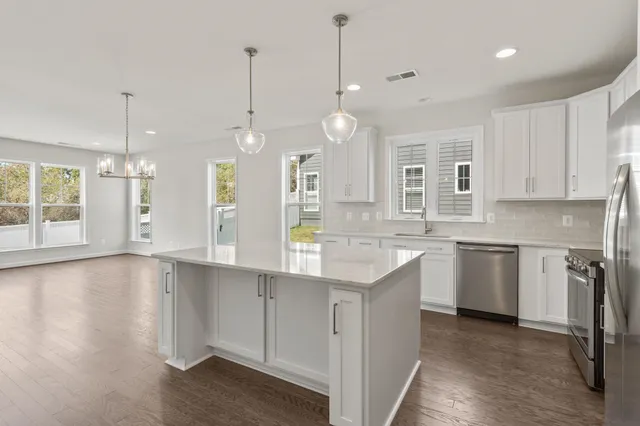 a view of a kitchen with stainless steel appliances granite countertop a sink a window and a wooden floor