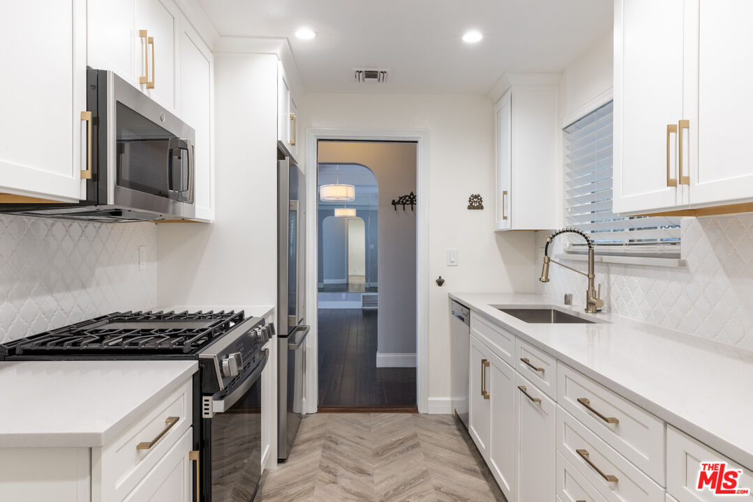 818 6th Street, Unit 102 Santa Monica, CA 90403 - Photo 6 of 29 a kitchen with stainless steel appliances a sink stove and cabinets