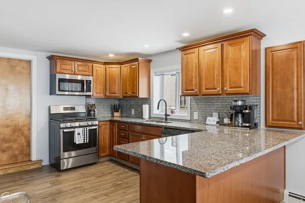 a kitchen with stainless steel appliances granite countertop a stove a sink and a microwave