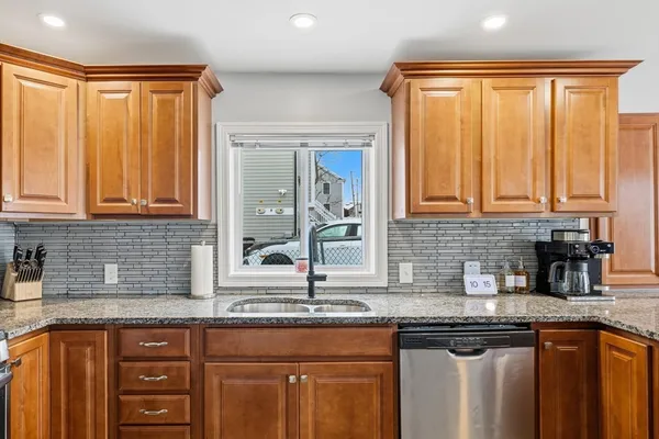 a kitchen with stainless steel appliances granite countertop a sink and dishwasher with wooden cabinets
