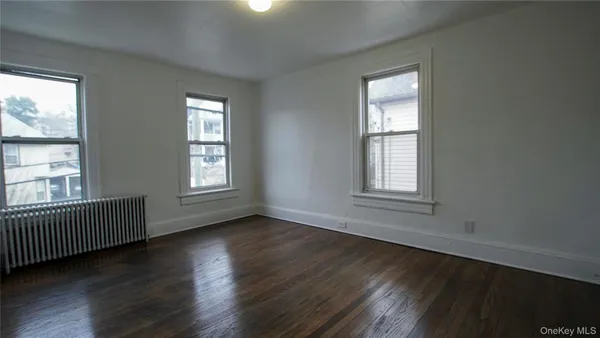 a view of an empty room with wooden floor and windows