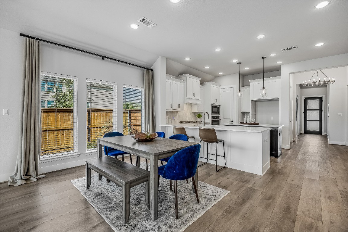 200 Grn Knl Lane Georgetown, TX 78628 - Photo 13 of 32 a kitchen with stainless steel appliances granite countertop a stove a sink a refrigerator a kitchen island with chairs and wooden floor