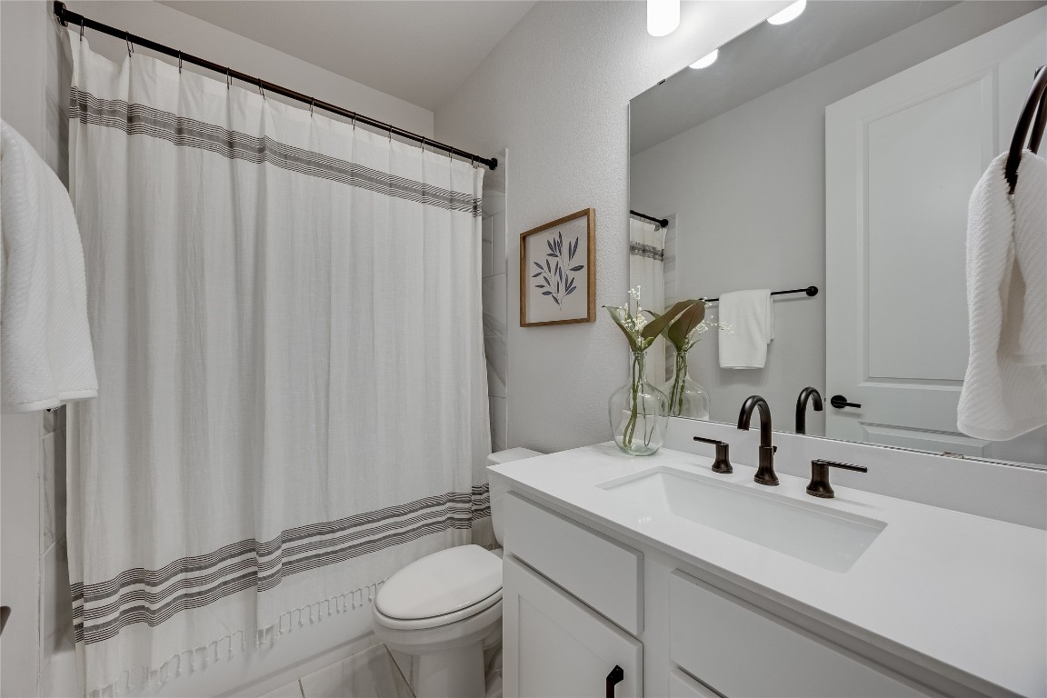 200 Grn Knl Lane Georgetown, TX 78628 - Photo 25 of 32 a bathroom with a sink a toilet a mirror and shower curtain