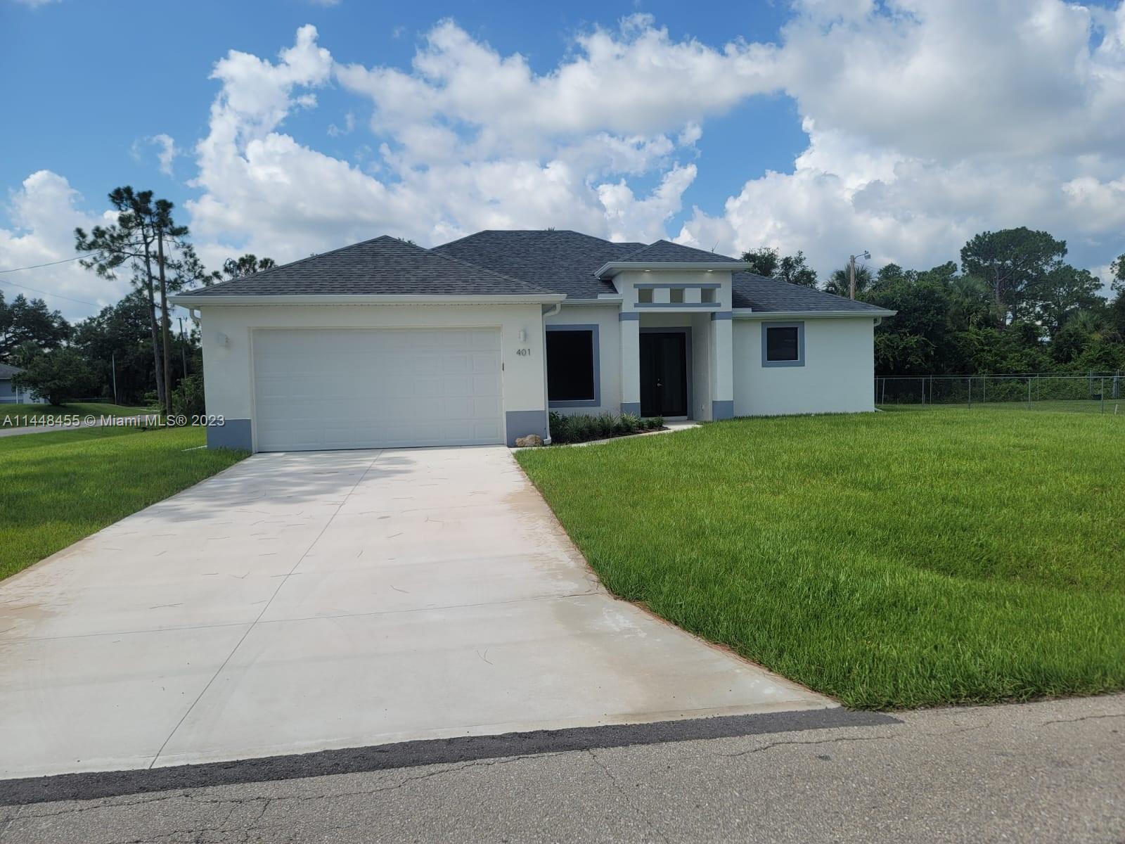 401 West 5th Street, Unit ST Lehigh Acres, FL 33972 - Photo 1 of 10 a view of a house with a yard and a garage