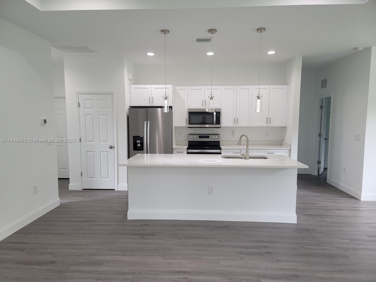 401 West 5th Street, Unit ST Lehigh Acres, FL 33972 - Photo 6 of 10 a view of kitchen with stainless steel appliances refrigerator stove microwave and cabinets