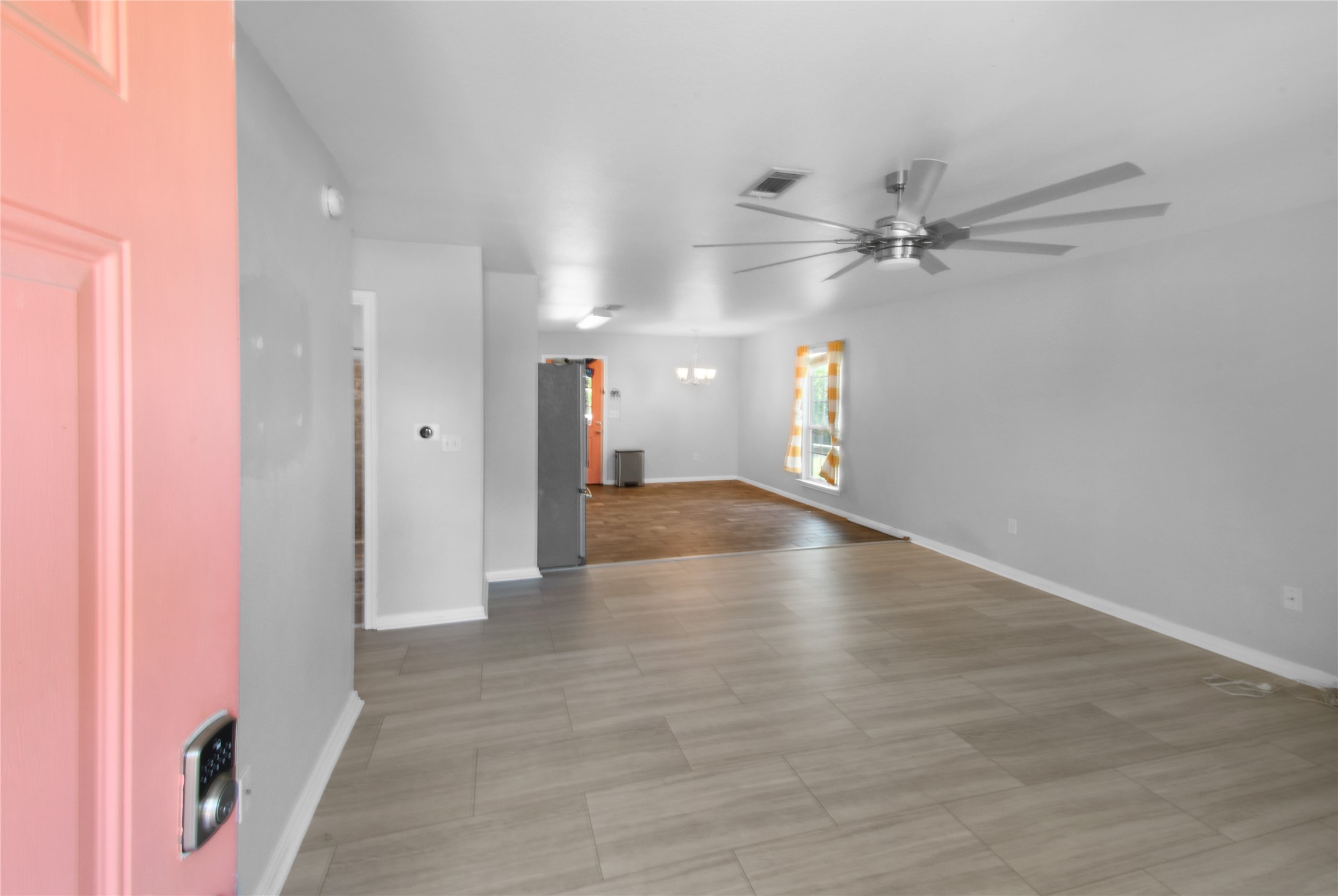 320 10th Street Dickinson, TX 77539 - Photo 12 of 21 Step into this inviting home through a vibrant front entry, unveiling a spacious, light-filled living area with modern flooring and a sleek ceiling fan, setting the stage for comfort and style.