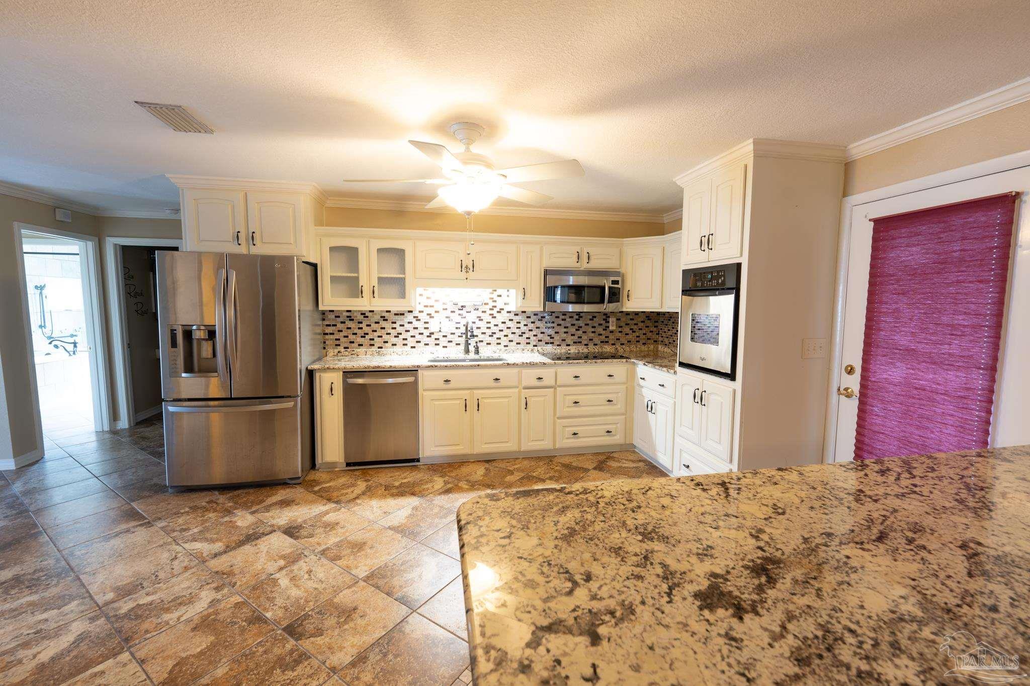 7608 River Road Milton, FL 32583 - Photo 14 of 28 a kitchen with granite countertop a refrigerator and a stove top oven