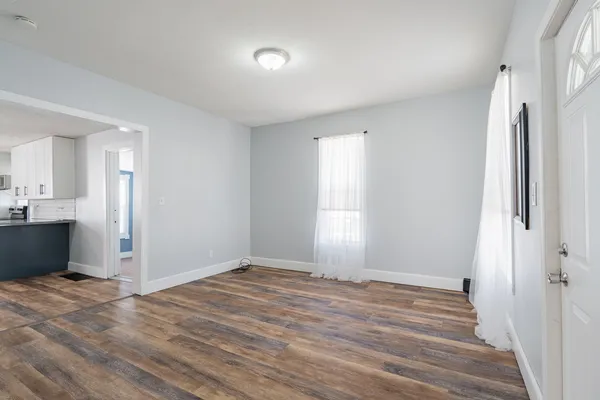 a view of kitchen and empty room with wooden floor