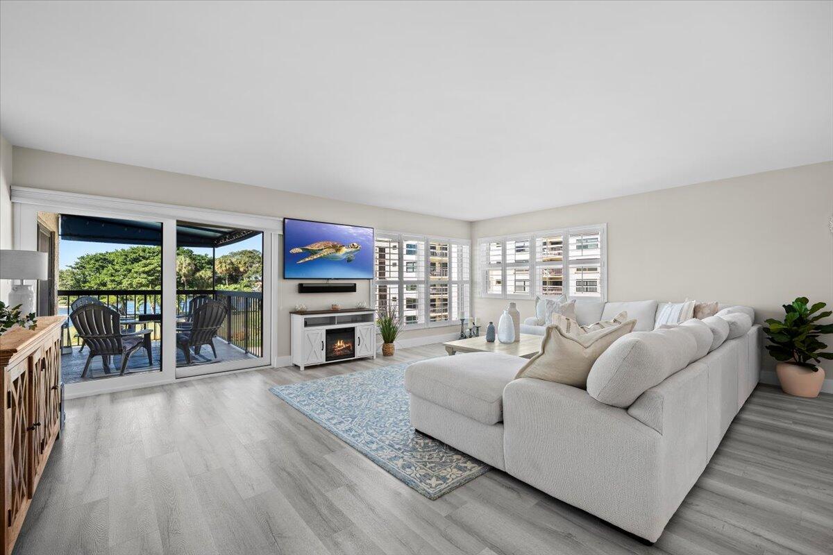 364 Golfview Road, Unit 405 North Palm Beach, FL 33408 - Photo 4 of 33 a living room with furniture a fireplace and a dining table with wooden floor