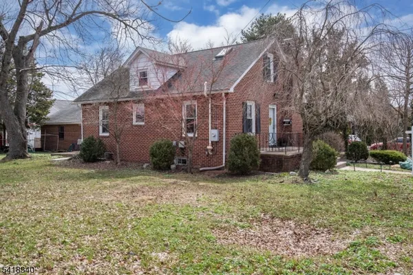 a view of a brick house with a yard and large trees