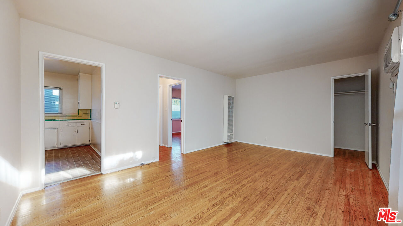 a view of an empty room with wooden floor and a bathroom