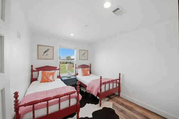 a bedroom with two beds and wooden floor