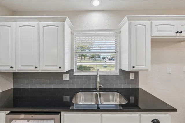 a kitchen with granite countertop white cabinets and a sink