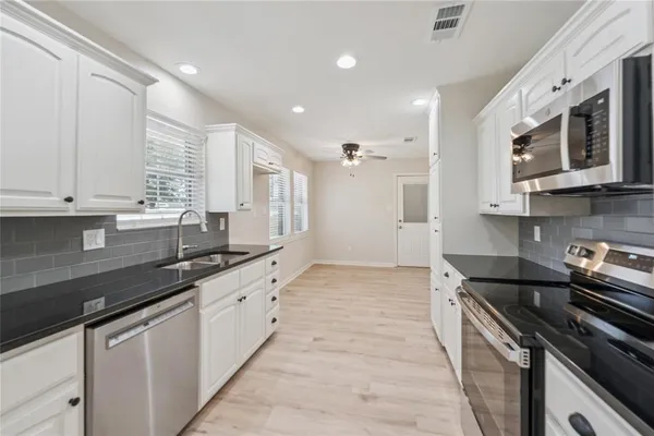 a large kitchen with stainless steel appliances granite countertop a sink and a stove