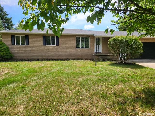 10089 Coldwater Road Flushing, MI 48433 - Photo 1 of 17 Brick exterior with a gabled roofline, multiple windows with dark shutters, a white entry door, and an attached garage with a dark door