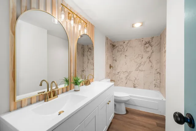 a bathroom with a sink a toilet and a large mirror