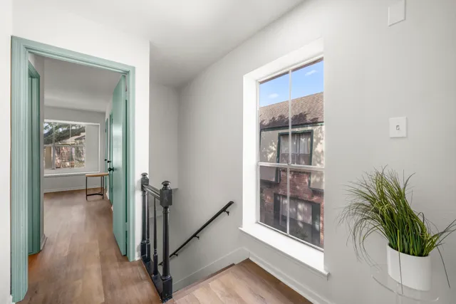 a view of a hallway with wooden floor and a potted plant