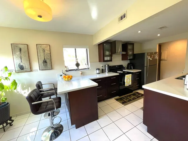 a kitchen with stainless steel appliances kitchen island granite countertop a sink and a refrigerator