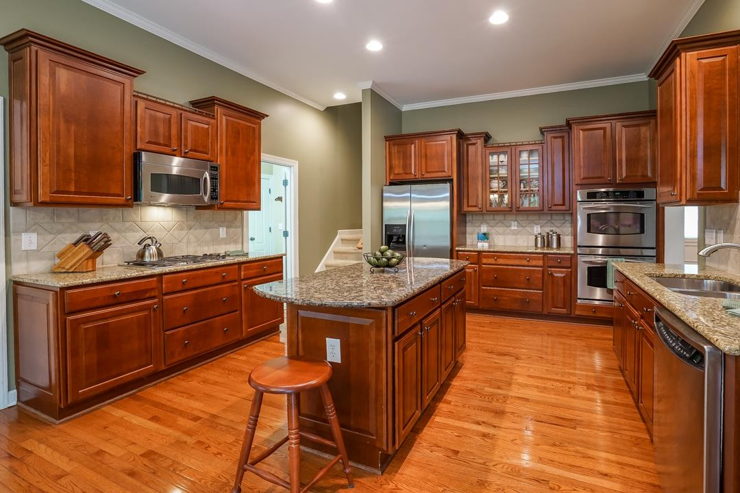 2920 Elmfield Street Raleigh, NC 27614 - Photo 11 of 30 Glass front cabinets for displaying dishes, tile backsplash, and center prep island with overhang on both ends for bar stools.