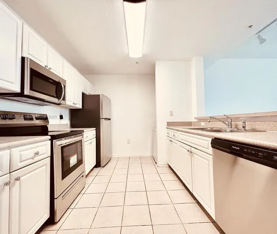 a kitchen with a sink a stove top oven and white cabinets