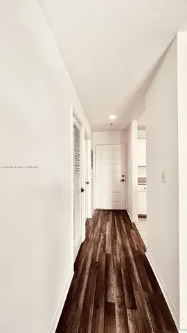 a view of a hallway with wooden floor and a bathroom