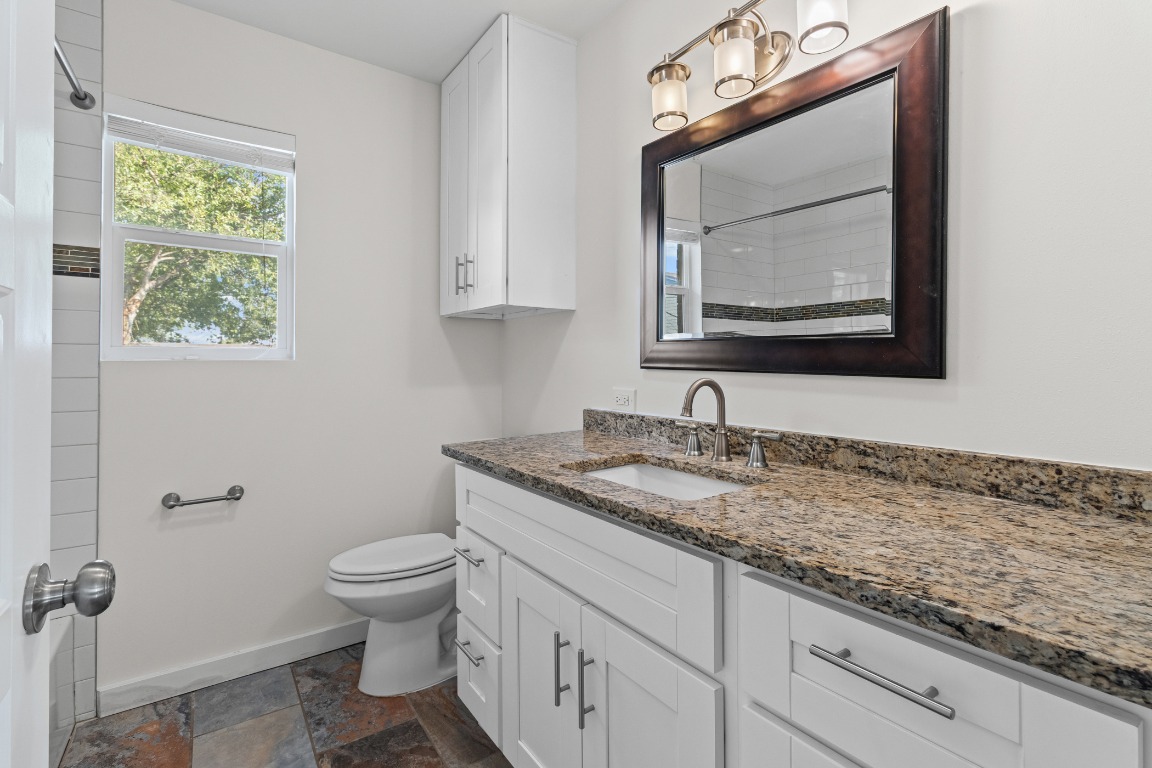 6305 Vioitha Drive, Unit B Austin, TX 78723 - Photo 14 of 23 a bathroom with a granite countertop toilet sink and mirror