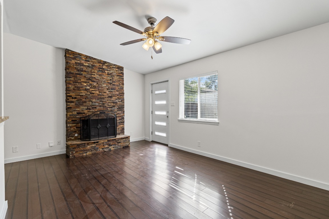 6305 Vioitha Drive, Unit B Austin, TX 78723 - Photo 2 of 23 an empty room with wooden floor a fireplace and windows