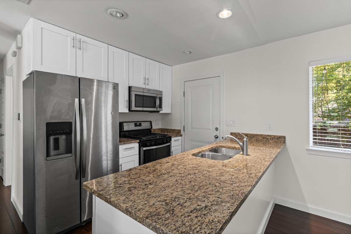 6305 Vioitha Drive, Unit B Austin, TX 78723 - Photo 7 of 23 a kitchen with granite countertop a refrigerator oven a sink dishwasher and microwave