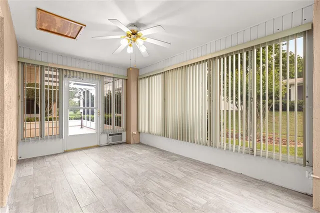 an empty room with wooden floor fan and windows