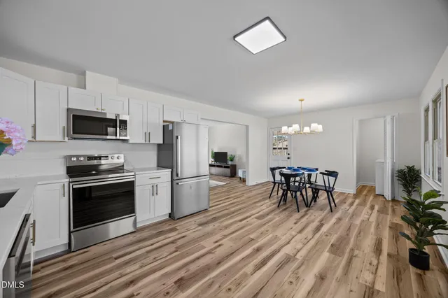 a kitchen with stainless steel appliances a dining table chairs stove and microwave