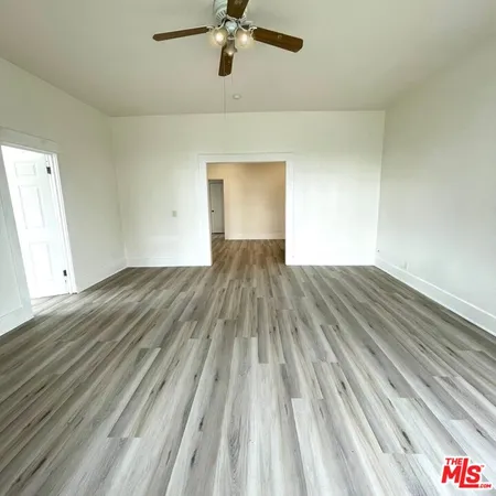an empty room with wooden floor fan and windows
