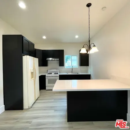 a large kitchen with stainless steel appliances kitchen island a stove a refrigerator a oven and a sink with large countertops