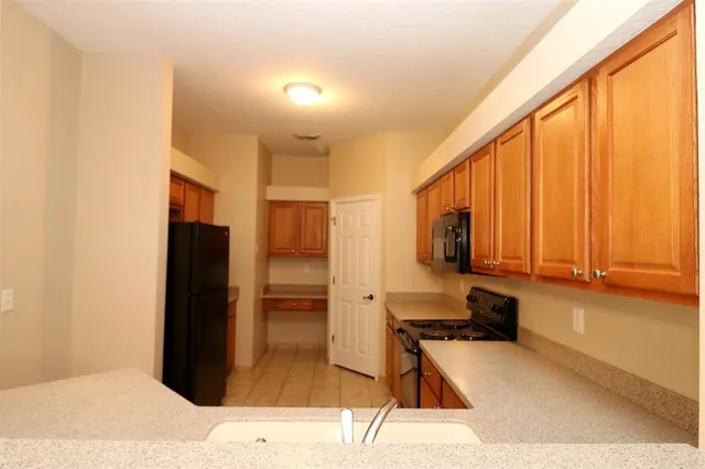 a kitchen with stainless steel appliances kitchen island granite countertop a refrigerator and a stove top oven