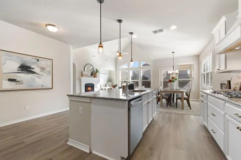 a kitchen with stainless steel appliances granite countertop a sink a stove and a wooden floor