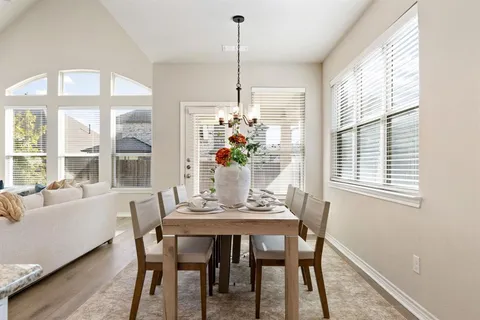a dining room with furniture a chandelier and wooden floor