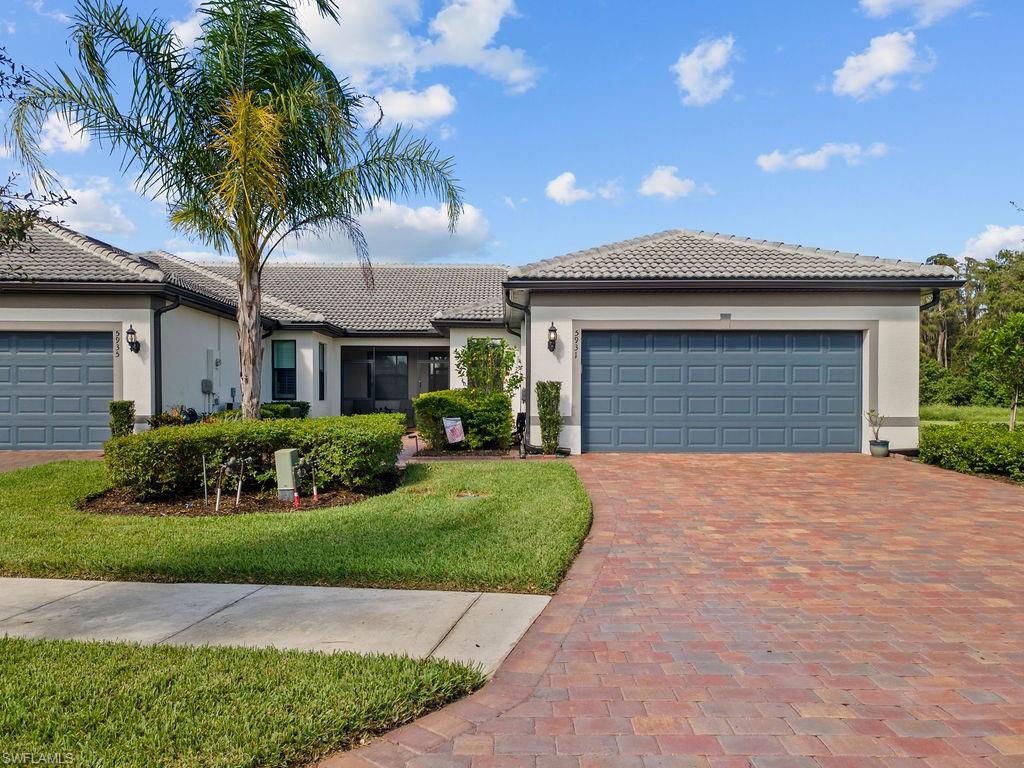 5931 Mayflower Way Ave Maria, FL 34142 - Photo 2 of 34 a front view of a house with a garden and palm tree