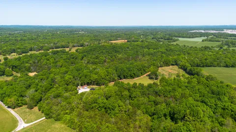 an aerial view of residential houses with outdoor space and trees all around