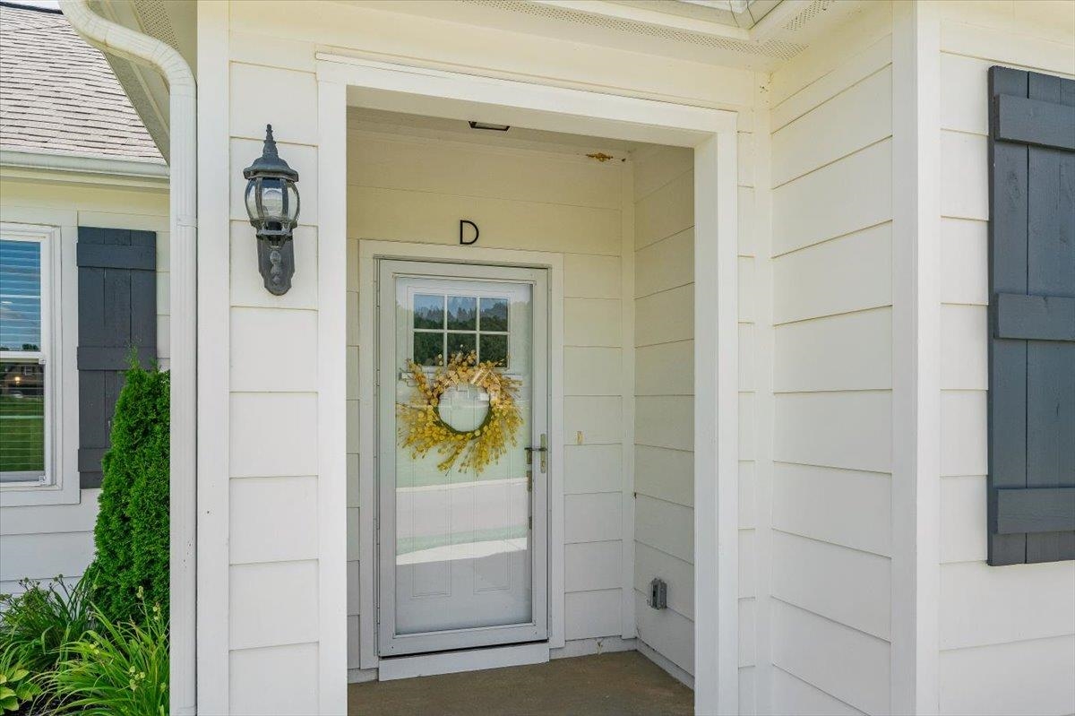 415 Abbey Road, Unit D Munford, TN 38058 - Photo 2 of 35 Front entry featuring a storm door, white siding, dark shutters, and an exterior wall lantern