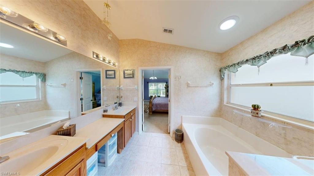 285 Spider Lily Lane Naples, FL 34119 - Photo 37 of 50 a bathroom with a tub a sink and mirror