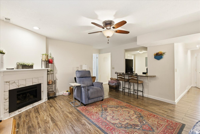 1334 Ridgewood Lane Bountiful, UT 84010 - Photo 27 of 38 Wood-finish flooring throughout, white fireplace with tile surround, ceiling fan with light fixture, recessed lighting, and a built-in bar counter