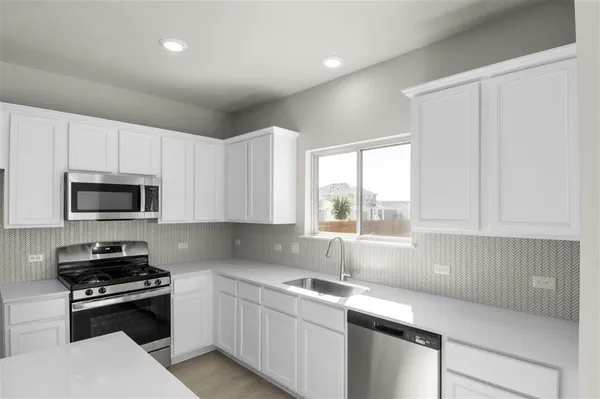 a kitchen with stainless steel appliances a sink a stove a microwave a refrigerator and cabinets